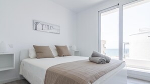 A modern bedroom with a large bed, a view of the sea, and a minimalist design. - 3-bedroom apartment with sea views, communal jacuzzi, next to the beach and close to the town center (Roses)