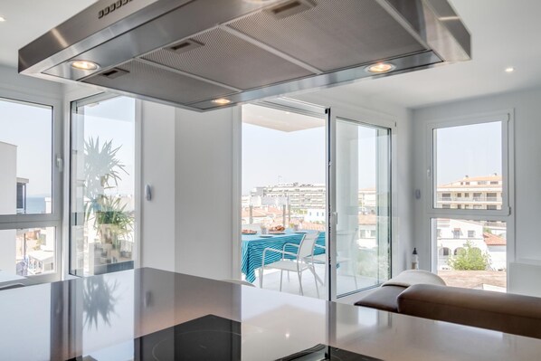 A modern kitchen with a large island, a stainless steel range hood, and a view of the city through large windows.