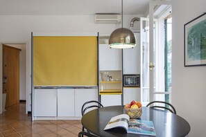 Cocina compacta con microondas, cafetera y un ventanal pequeño.