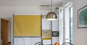 A compact kitchen with a yellow partition, a microwave, and a hanging light fixture. - Ca' del Porto by Wonderful Italy (Santa Margherita Ligure)