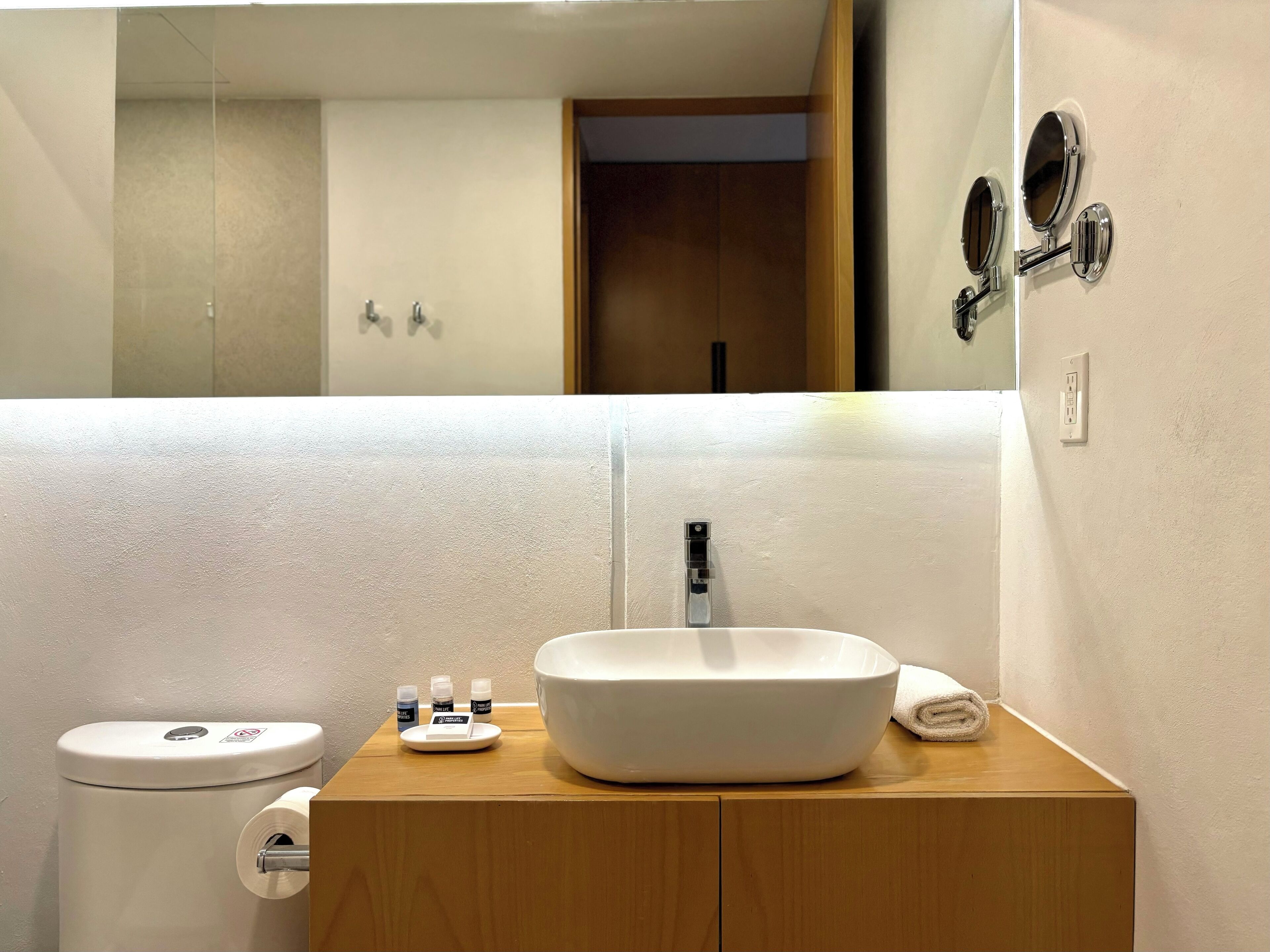 Un baño con lavamanos, inodoro y espejo blancos.