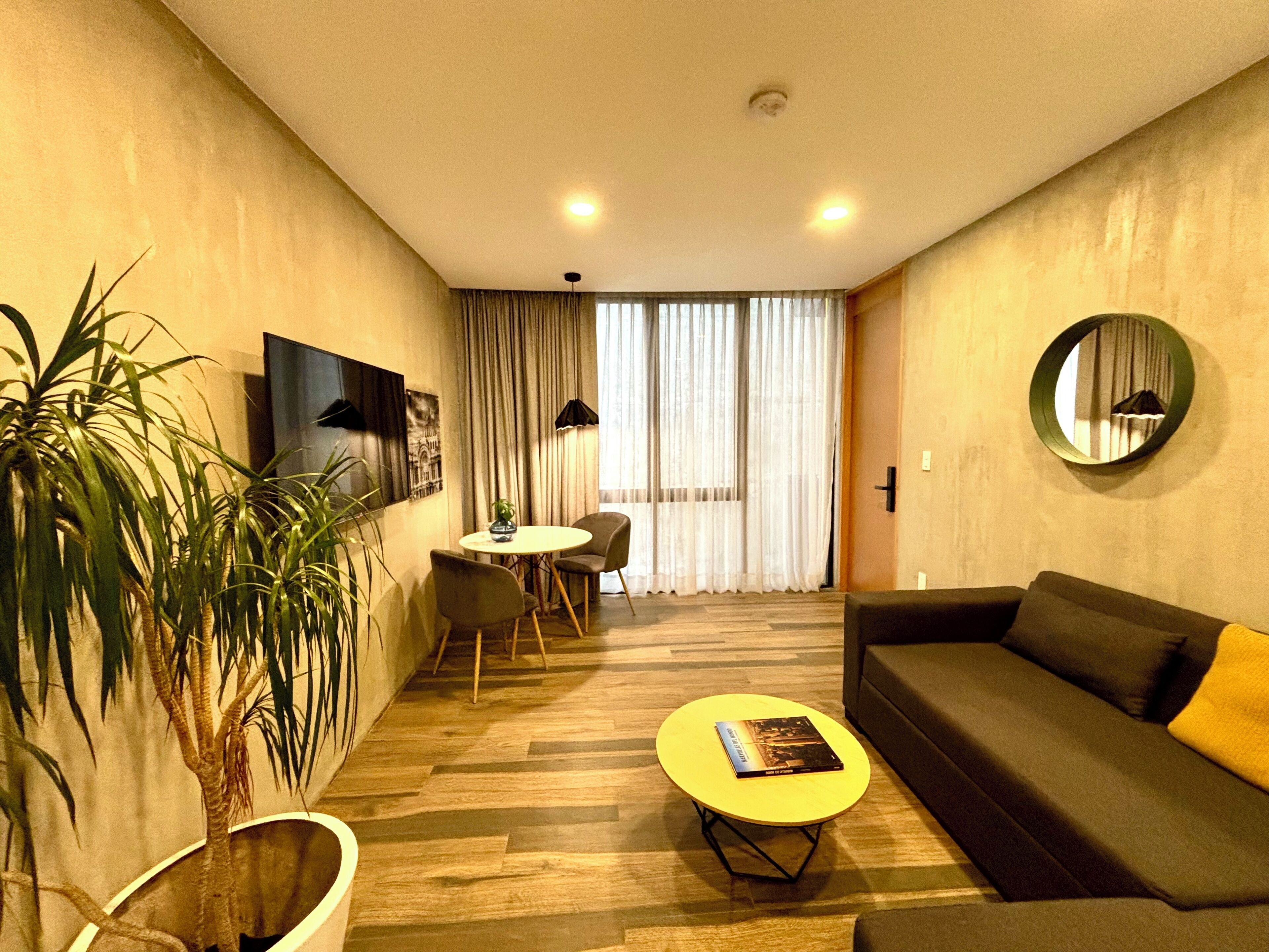 A modern living room with a sofa, a coffee table, and a dining area with a table and chairs.