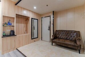 A modern living room with a brown leather sofa, wooden cabinets, and a tiled floor.