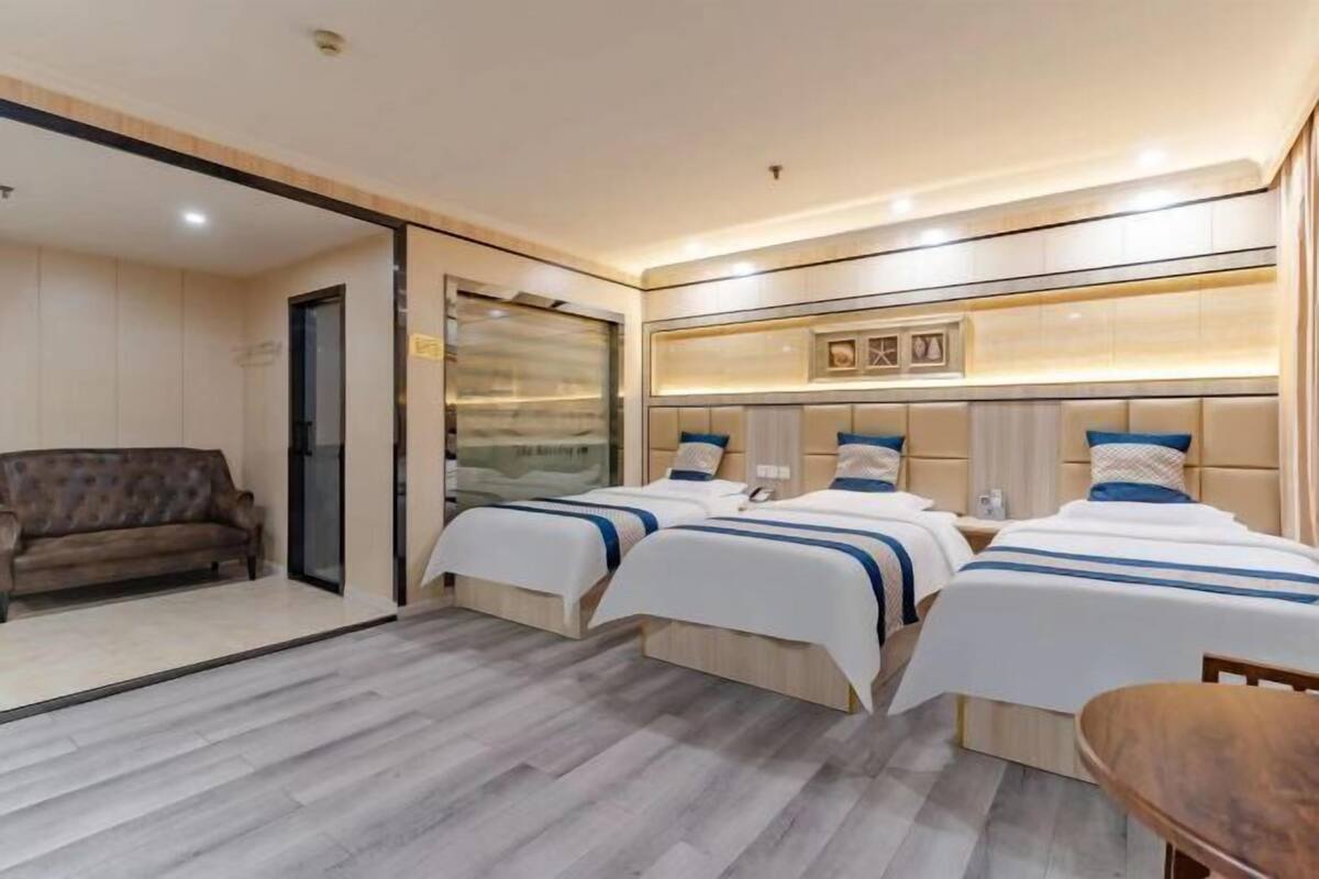 Habitació d'hotel amb dos llits, un sofà i una taula de fusta.