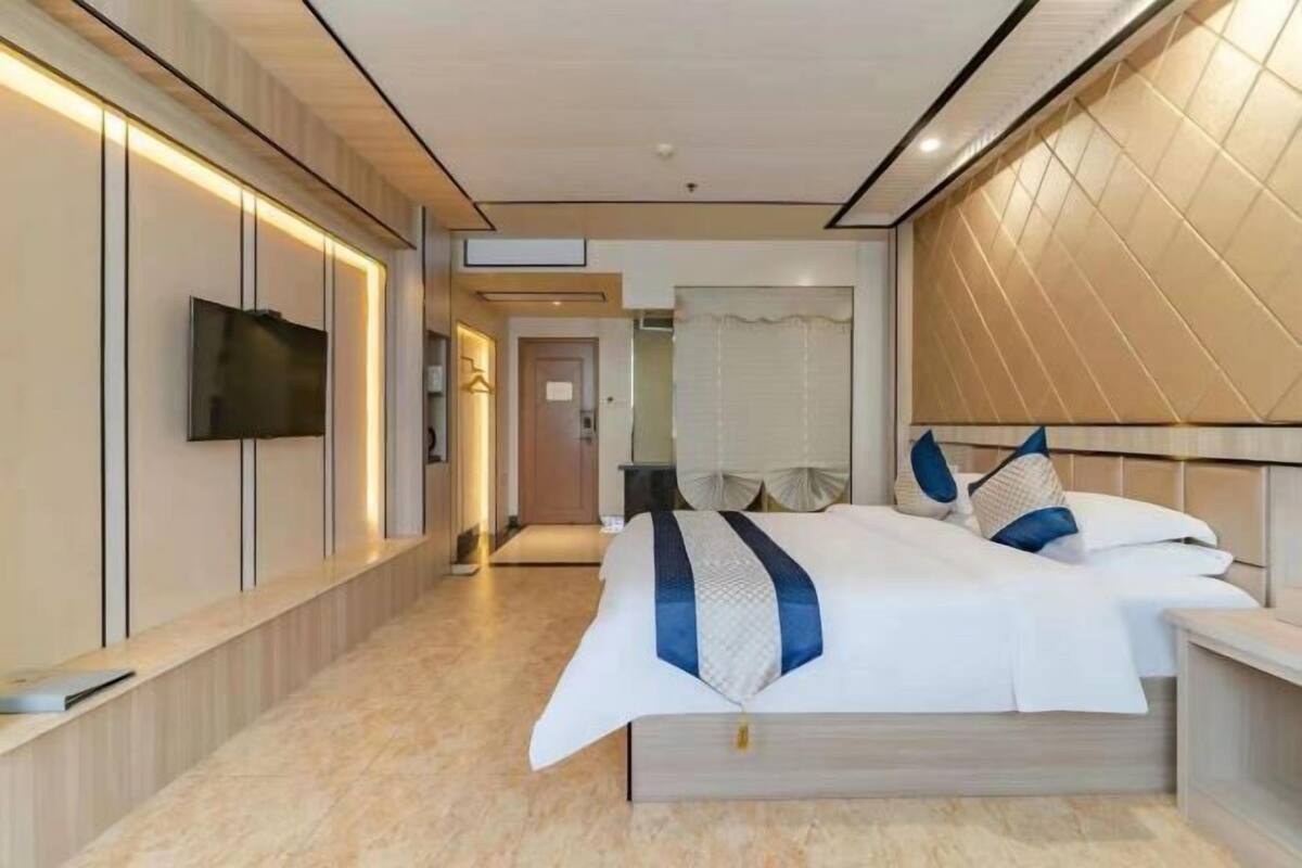 Habitació d'hotel moderna amb un llit gran, televisió de pantalla plana i un armari encastat.