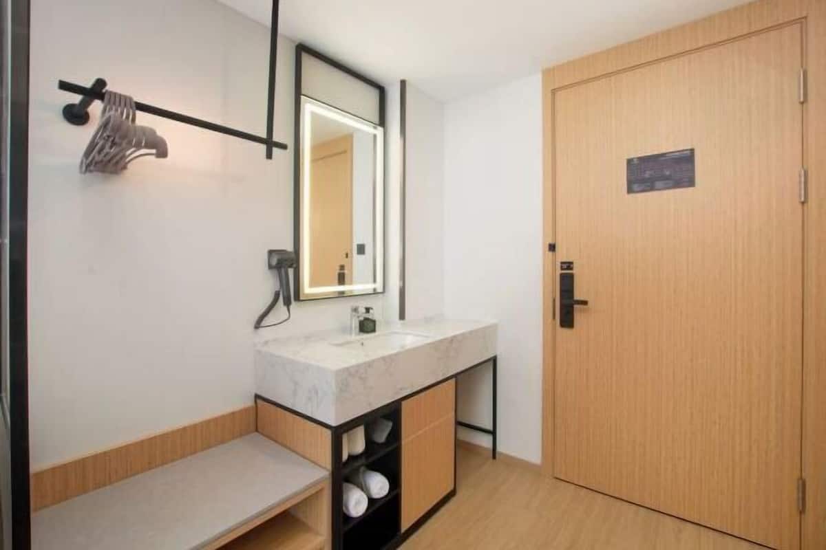 Une salle de bain moderne avec un lavabo en marbre, un porte-serviettes, un miroir et une porte en bois.