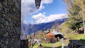 A stone pathway leading to a rustic building with a mountain backdrop.