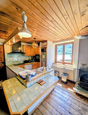 Una cocina con gabinetes de madera, microondas integrado y un amplio ventanal.