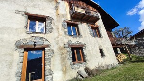 A rustic building with stone walls, wooden balconies, and multiple windows.