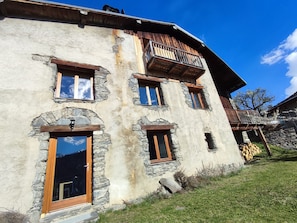 Un edificio rustico con pareti in pietra, balconi in legno e numerose finestre.