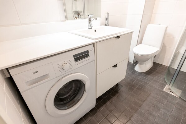 A modern bathroom with a white washing machine, a sink, and a toilet.