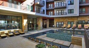 Relax by the pool with a clear view of the surrounding building, surrounded by lounge chairs.