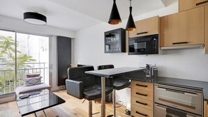 Une cuisine moderne dotée d’un coin repas, avec un plan de travail noir, des appareils en acier inoxydable et des meubles en bois.