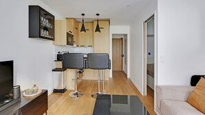 Un appartement moderne comprenant une cuisine, deux chaises noires, un canapé et un téléviseur.