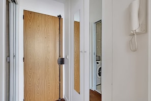 Eine Holztür mit Schiebesystem, ein weißes Wandtelefon und ein Spiegelbild einer Waschmaschine.