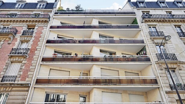Un immeuble à plusieurs étages doté de balcons, de grandes fenêtres et d’un style architectural classique.