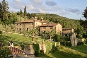 A stone building with a tiled roof, surrounded by greenery and hills. - Villa Grassina (Pelago)