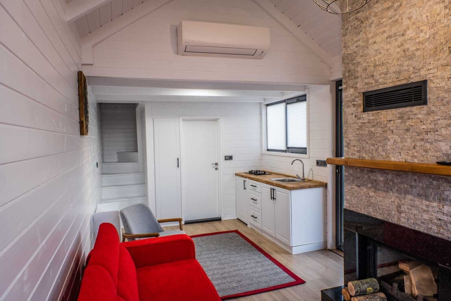 A compact kitchen with white cabinets, a wooden countertop, and a window above the sink.