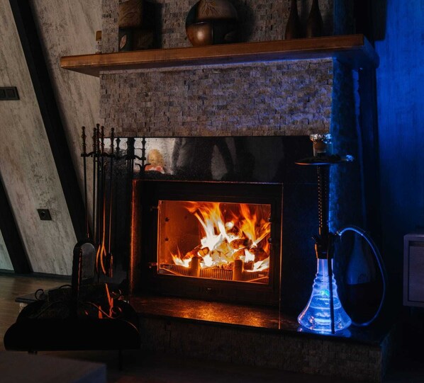A wood-burning stove with a visible fire, a hookah on the right, and a brick wall.