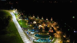 Een resort met meerdere accommodaties in chalethuizen, een centraal gelegen zwembad en een goed verlicht pad naar de gebouwen.