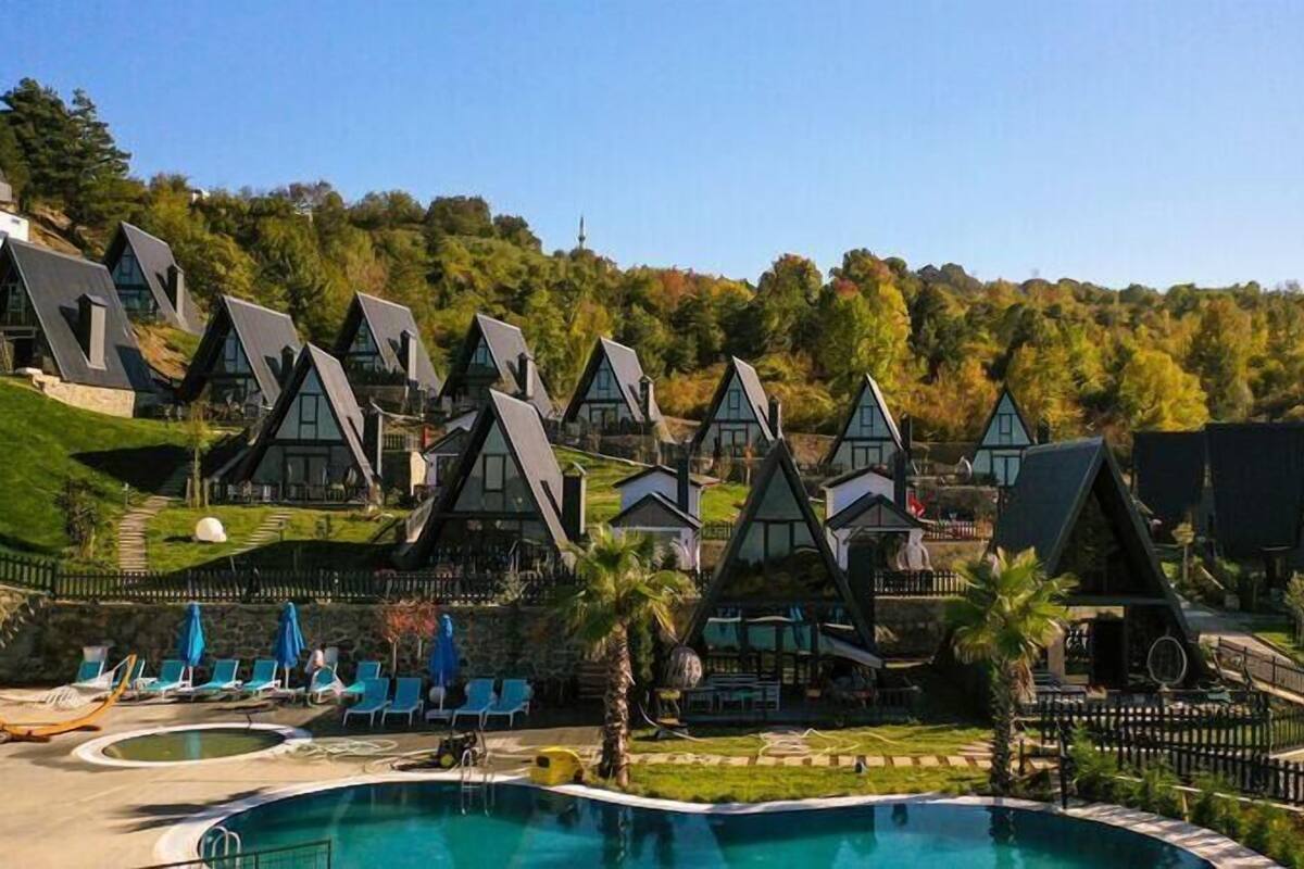 Ein Resort mit mehreren Chaletgebäuden, einem Swimmingpool und einer Hanglage im Hintergrund.