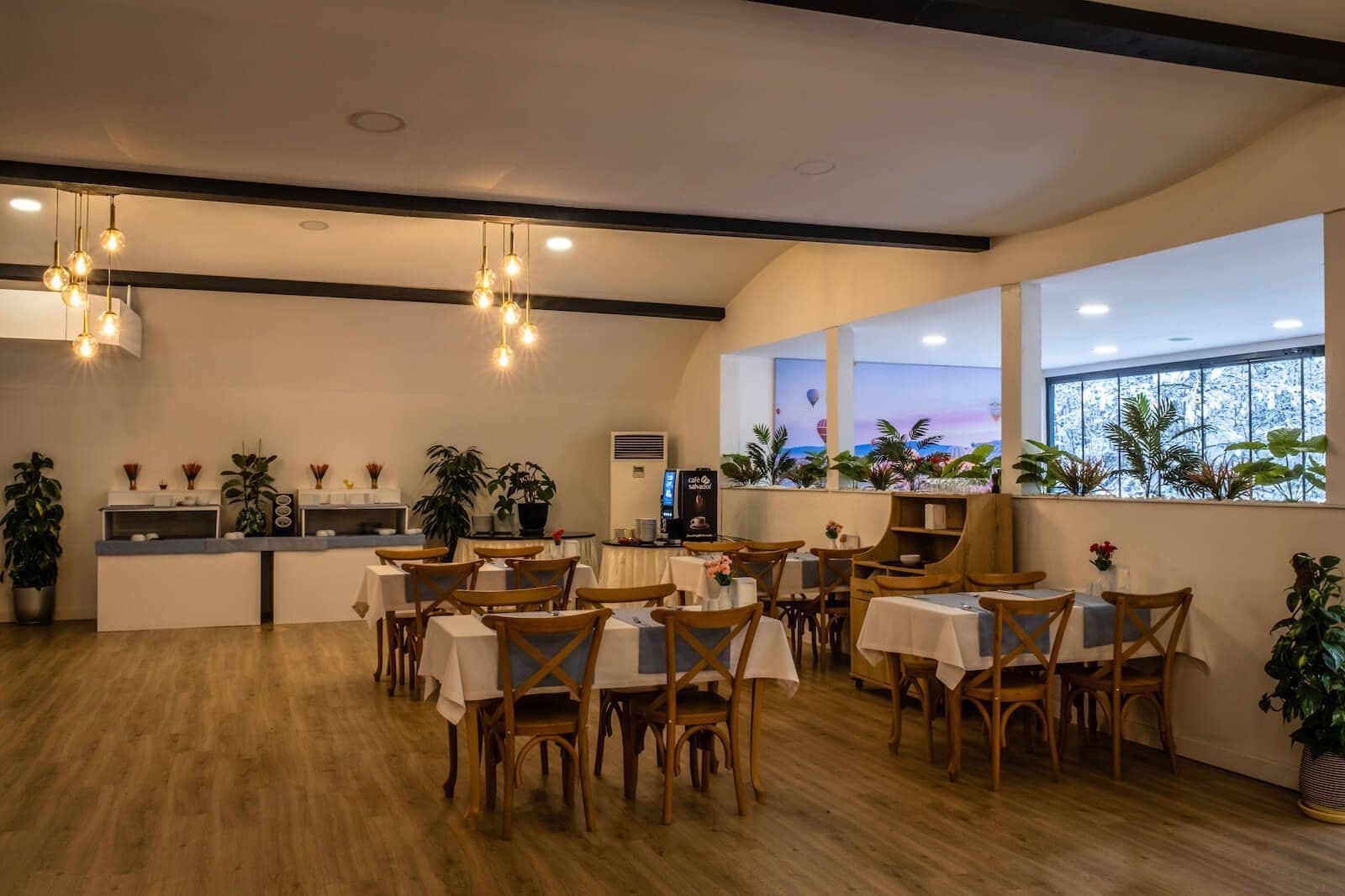 A restaurant with wooden tables and chairs, a counter with a menu, and large windows with a view.