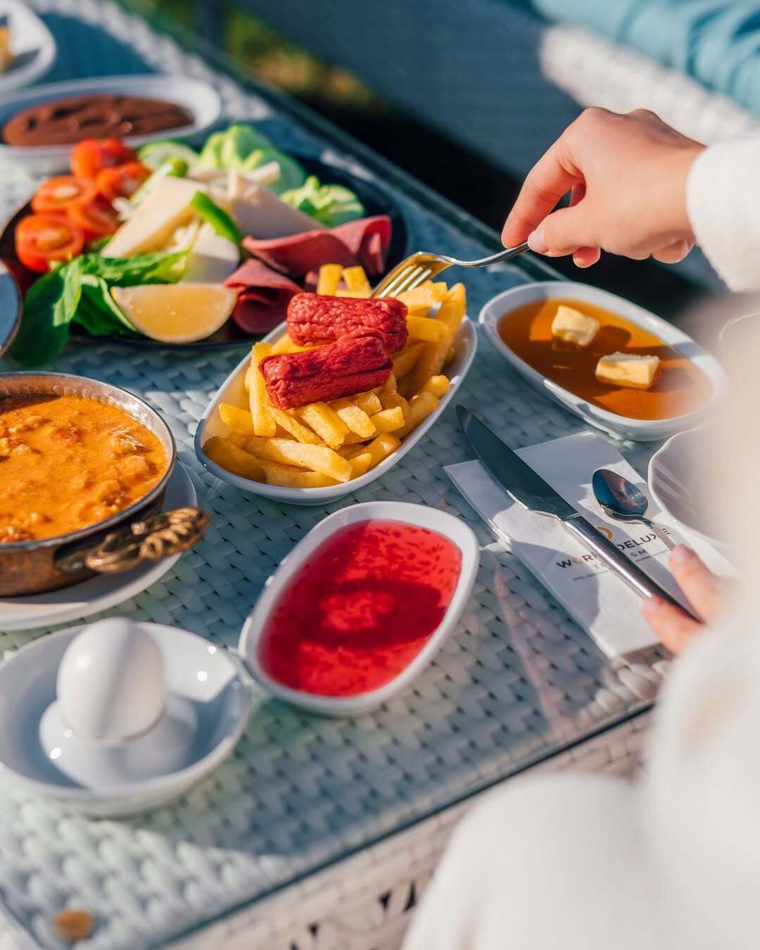 A table with various dishes including fries, a red sauce, and a bowl of soup.