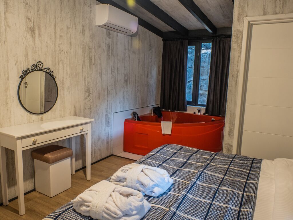 Un dormitorio con una cama, un escritorio, una bañera roja y una ventana con cortinas.