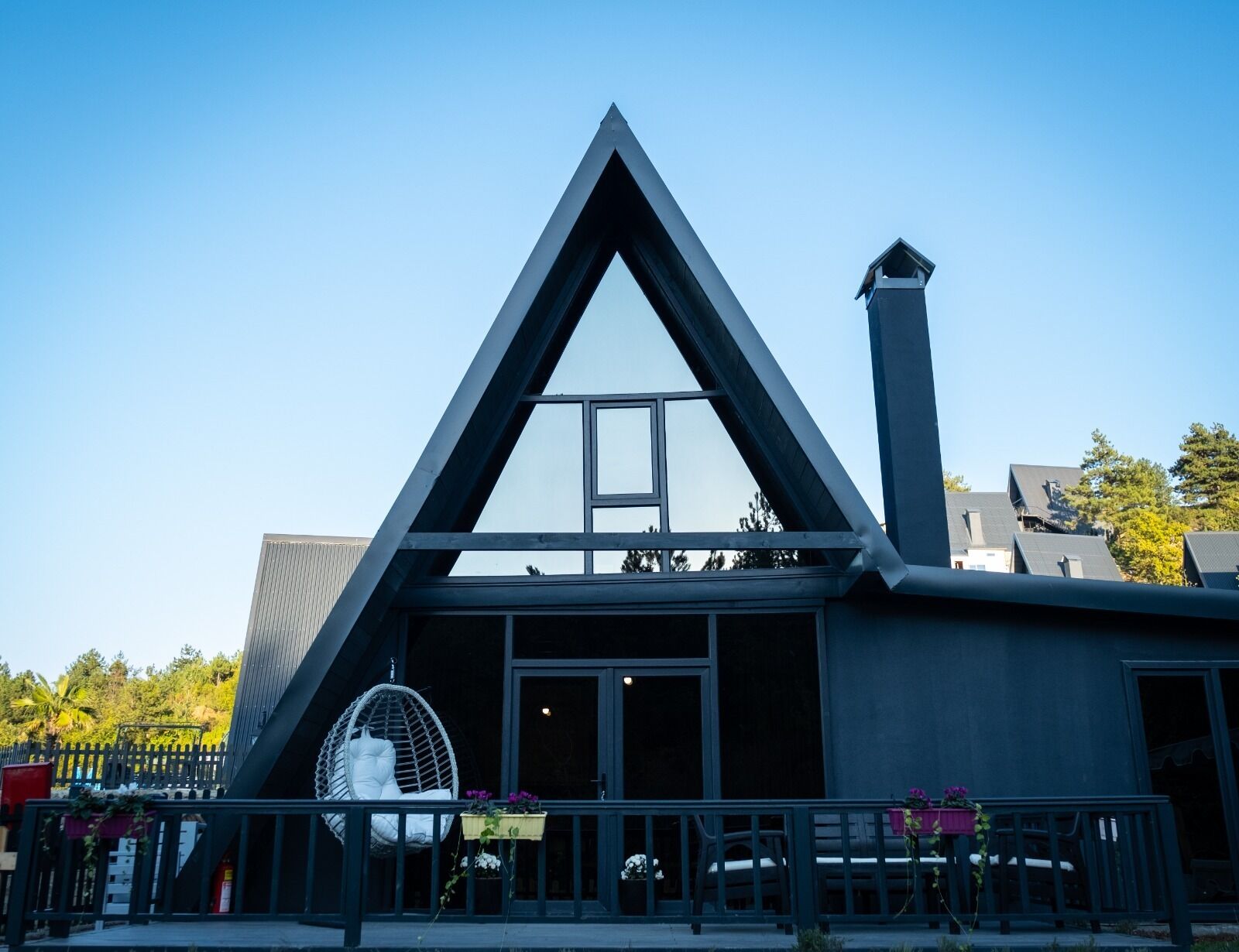 A modern building with a triangular facade, large windows, and a balcony with seating.