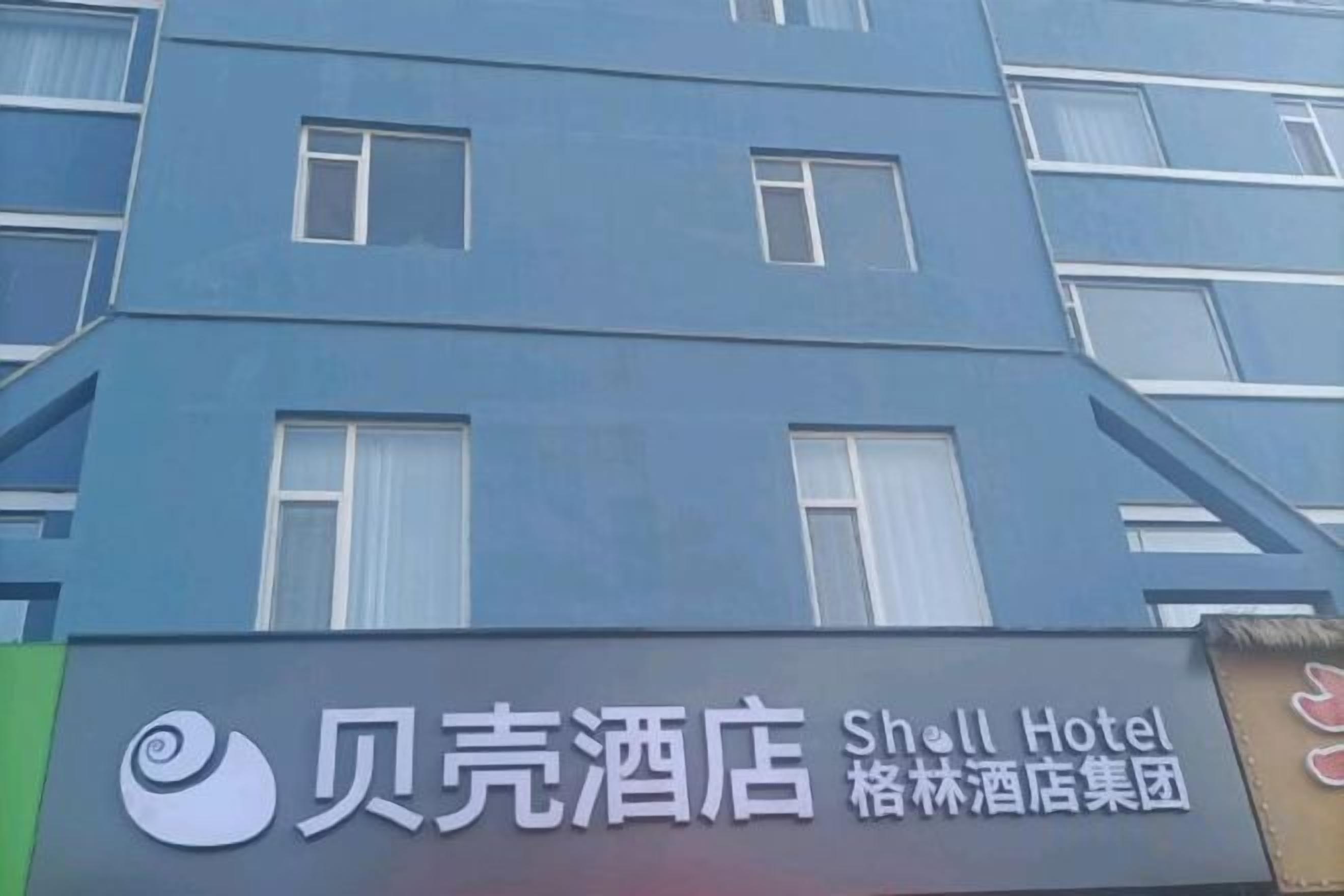 Un letrero de hotel con el nombre '贝克酒店' y 'Shill Hotel', indicando que forma parte de una cadena hotelera.