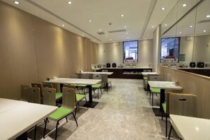 A modern dining area with tables and chairs, a kitchen area, and a large mirror on the wall. - GreenTree Shell Hotel (Yantai University Yingchun Street) (Yantai)