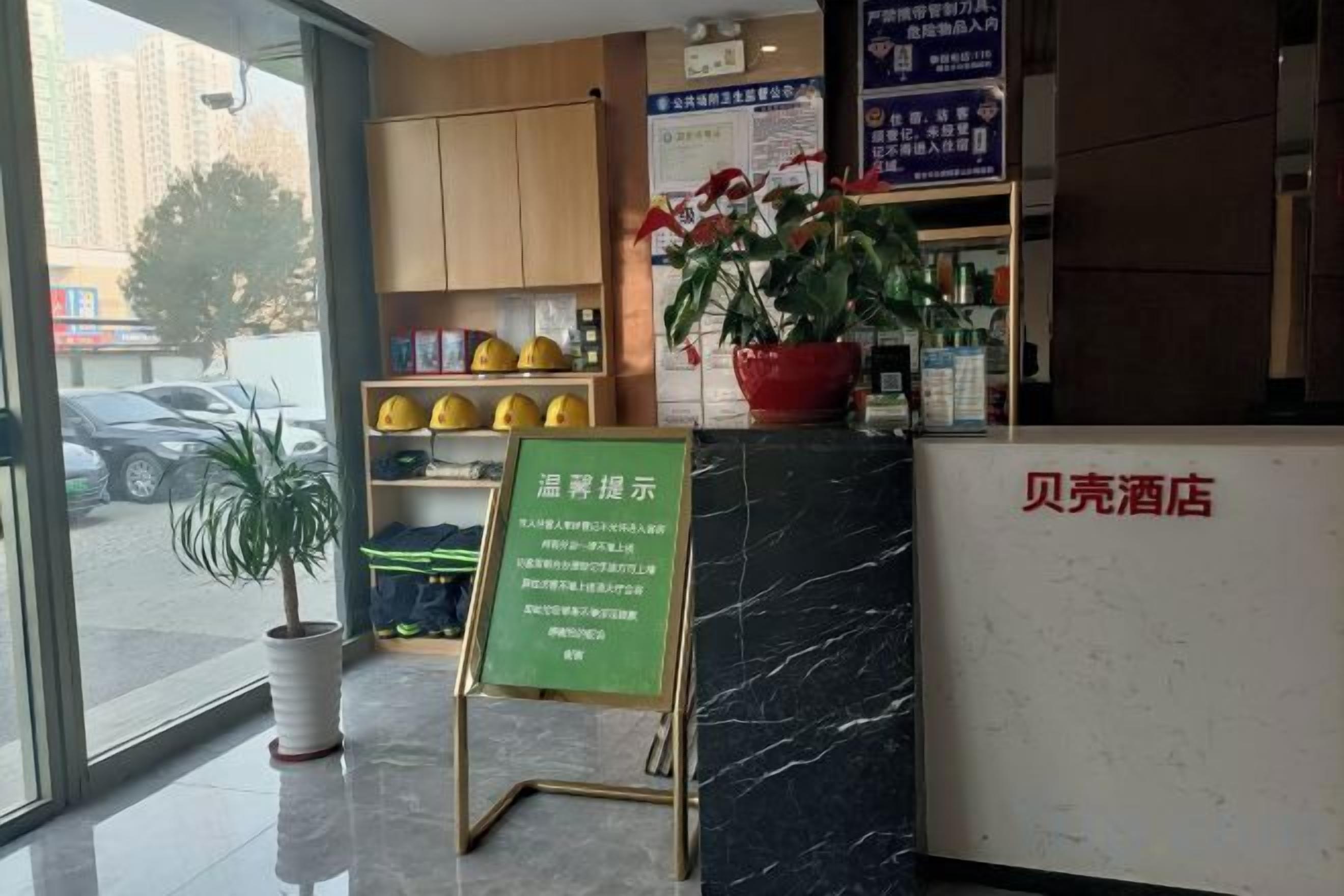 A hotel reception area with a marble counter, a green information stand, and a potted plant.