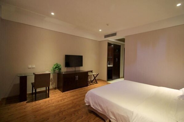 A bedroom with a bed, a desk, a chair, a television, and a wardrobe.