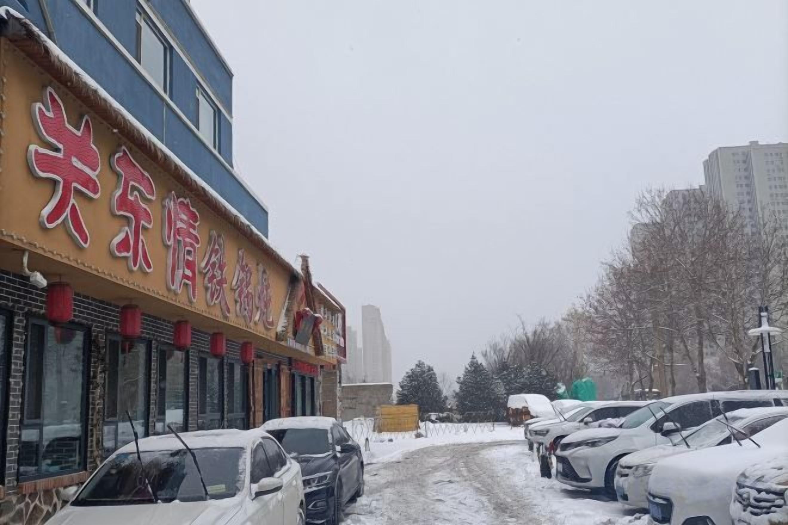 Une rue bordée de voitures garées et un immeuble avec une enseigne.