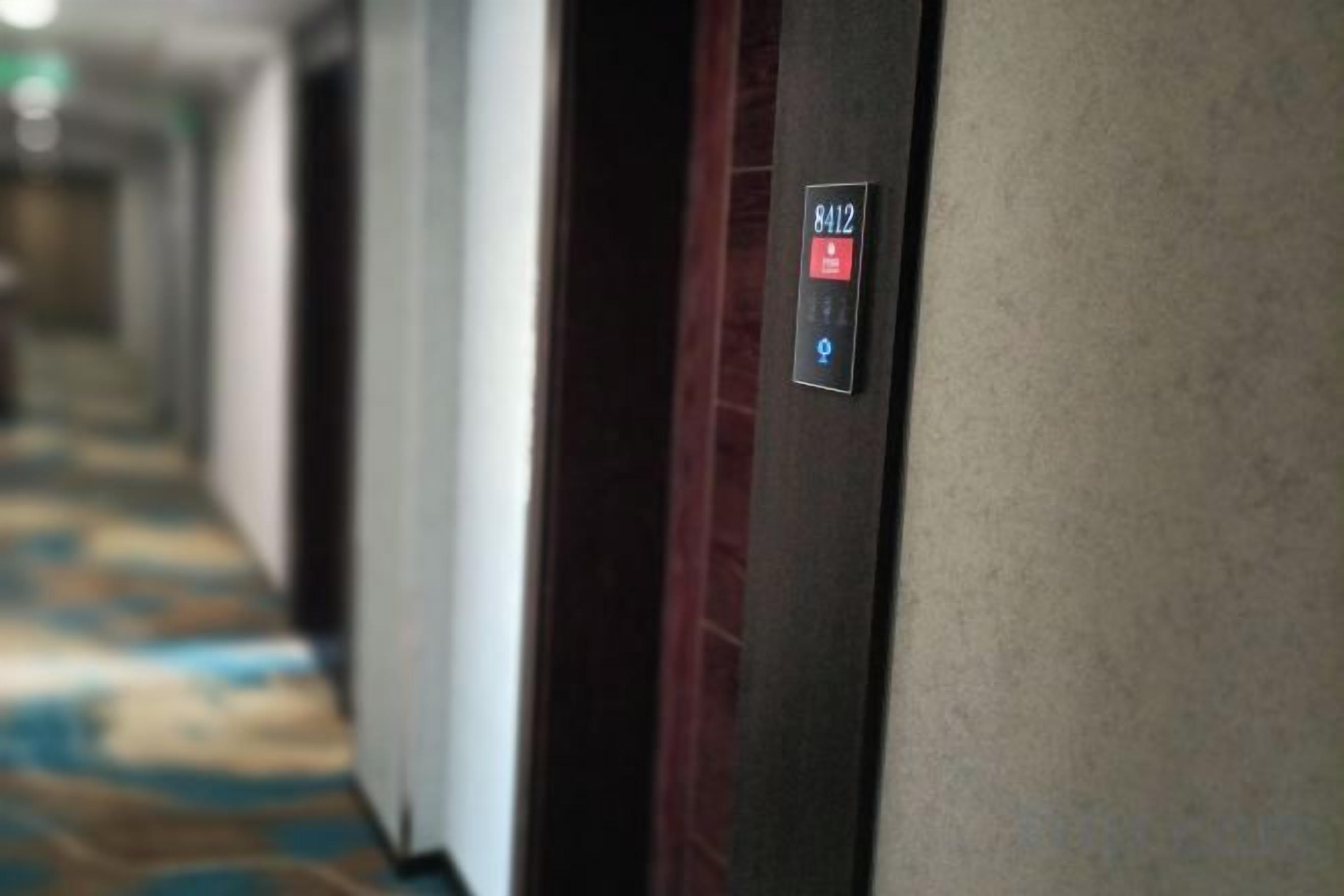 Un couloir d’hôtel avec une porte portant le numéro « 8412 » et un sol recouvert de moquette.