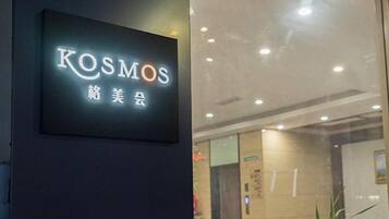 A sign with the word 'KOSMOS' and some non-English characters, indicating a hotel or business establishment.
