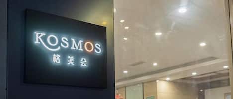 Une enseigne portant le mot « KOSMOS » et quelques caractères qui ne sont pas de l’alphabet anglais, indiquant un hôtel ou un établissement commercial.