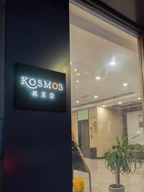 A sign with the word 'KOSMOS' and some non-English characters, indicating a hotel or business establishment.