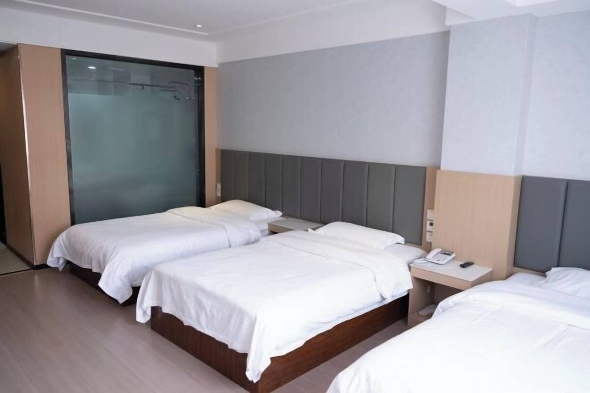A hotel room with two beds, a bedside table with a phone, and a sliding door.