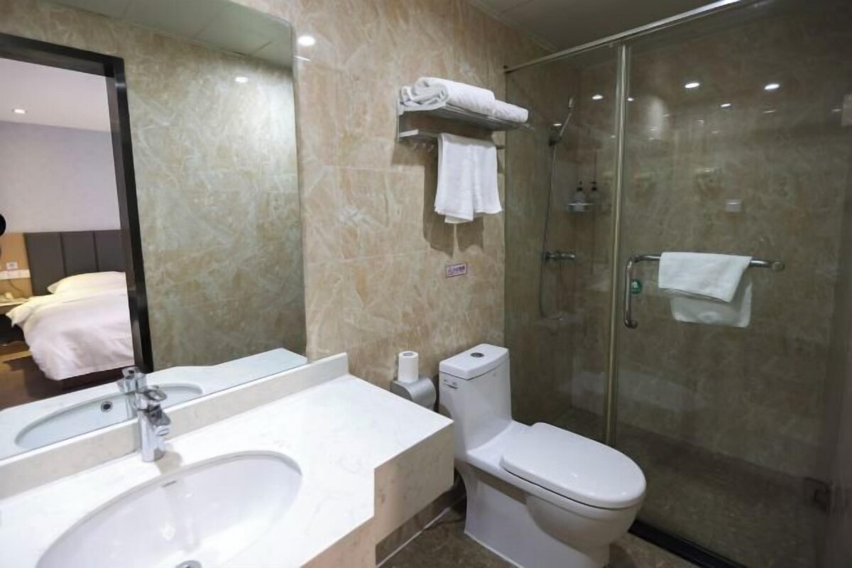 A modern bathroom with a marble sink, a toilet, and a glass-enclosed shower.