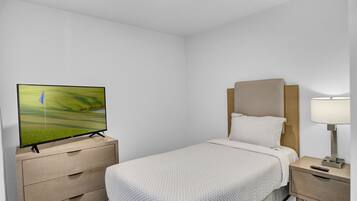 Ein Hotelzimmer mit einem Bett, einem Fernseher auf einem Schrank, einem Nachttisch mit Lampe und einem Holzkopfteil.
