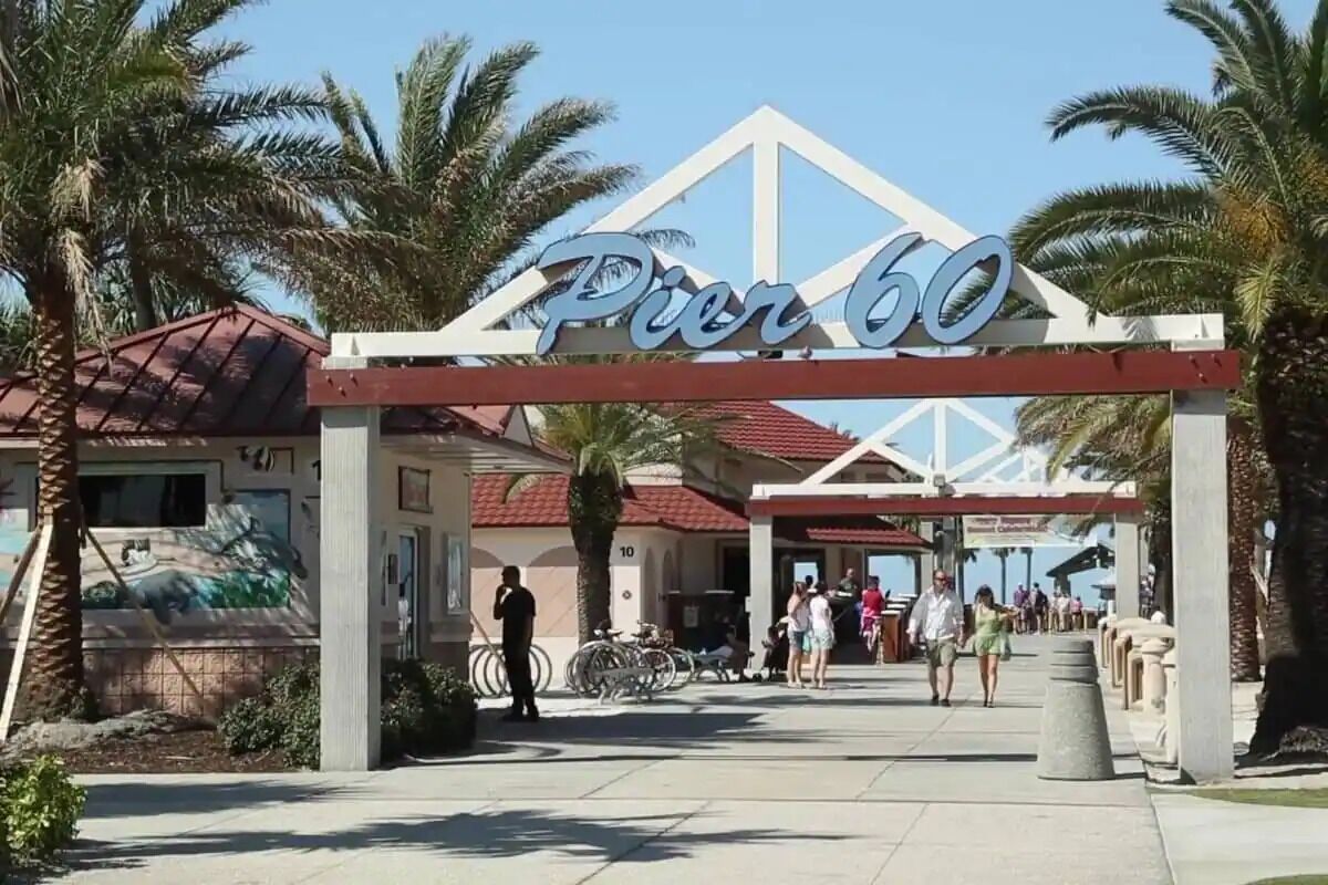 A sign reading "Pier 60" with a white arch and palm trees in the background.