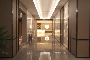 A hotel lobby with a reception desk, a plant, and a reflective floor. - Taoyuan International Hotel (Dazhou)
