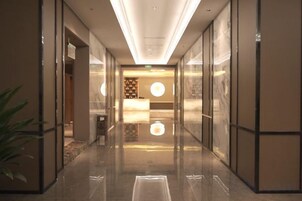 Un vestíbulo de hotel con una recepción, una planta y un suelo reflectante.