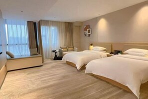 A hotel room with two beds, a sofa, a small table, and a window with curtains. - Taoyuan International Hotel (Dazhou)
