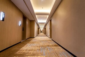 Pasillo de hotel con pisos alfombrados, puertas a ambos lados e iluminación en el techo.
