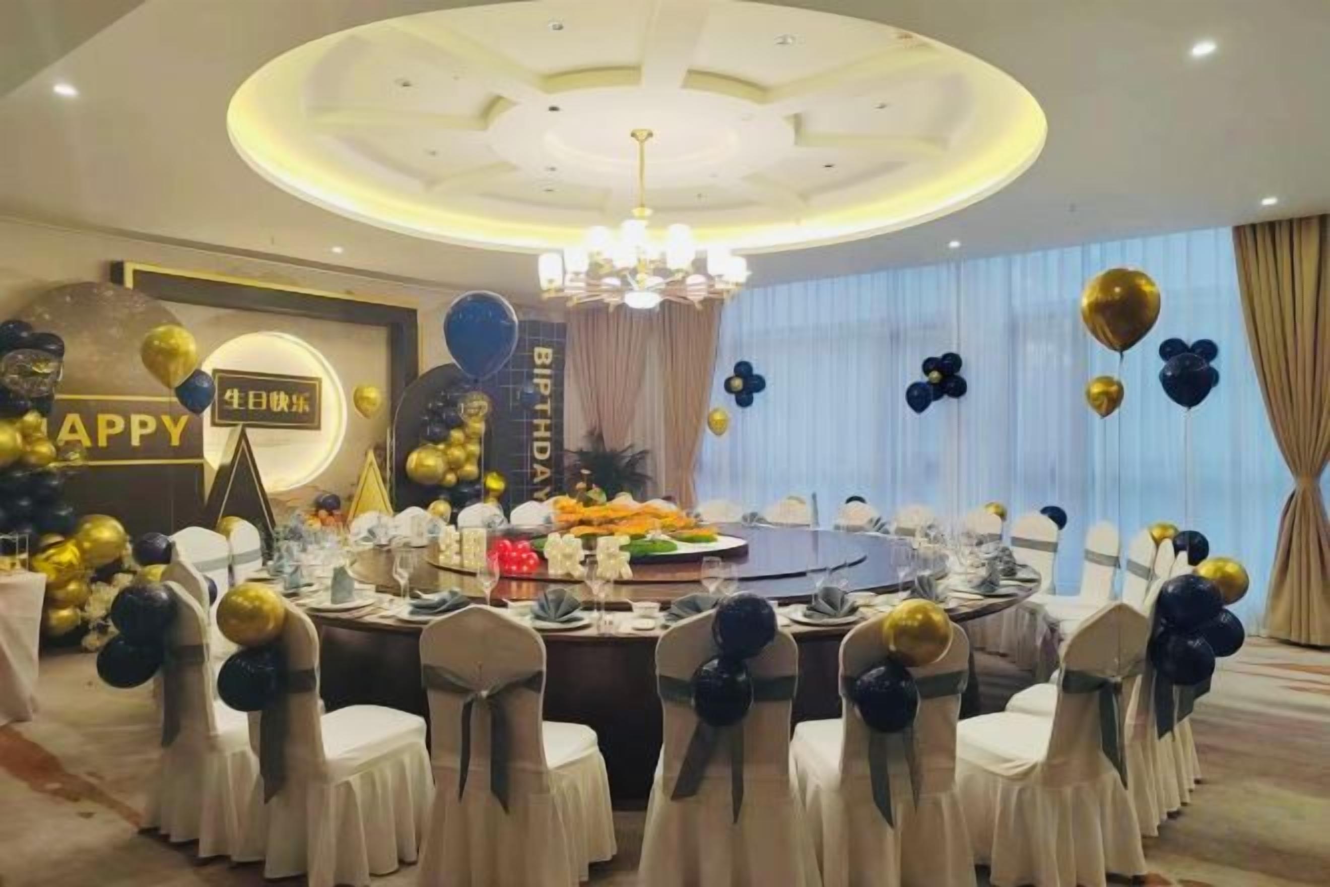 A banquet hall with round tables, white tablecloths, and chairs with black and white sashes.
