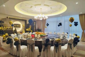 Un salón de banquetes con mesas redondas, manteles blancos y sillas con cintas negras y blancas.