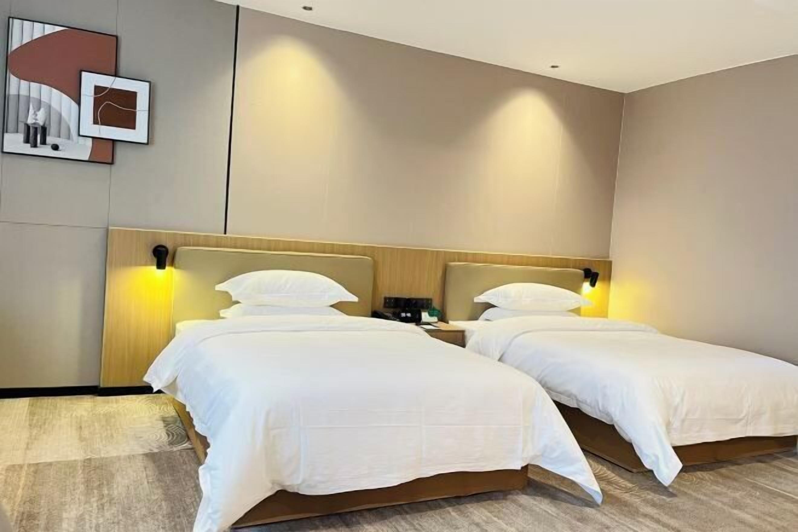 Quarto de hotel com duas camas de solteiro, cabeceira de madeira, mesas de cabeceira e uma obra de arte na parede.
