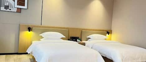 A hotel room with two single beds, a wooden headboard, bedside tables, and a wall-mounted artwork.